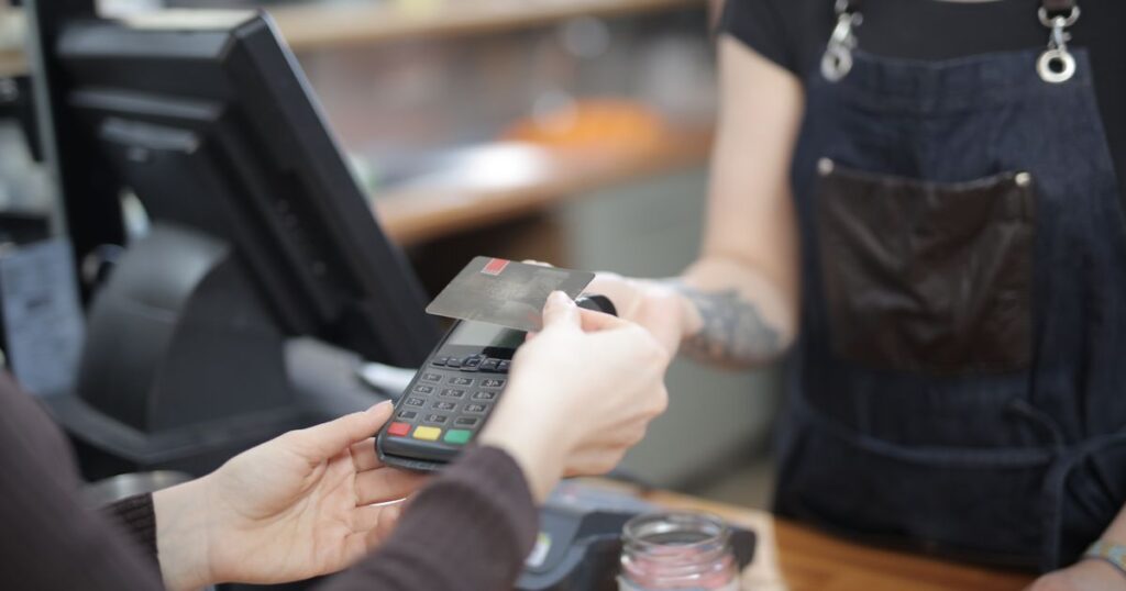 Customer paying by card at a shop counter, representing the cost of winning a new customer