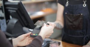 Customer paying by card at a shop counter, representing the cost of winning a new customer