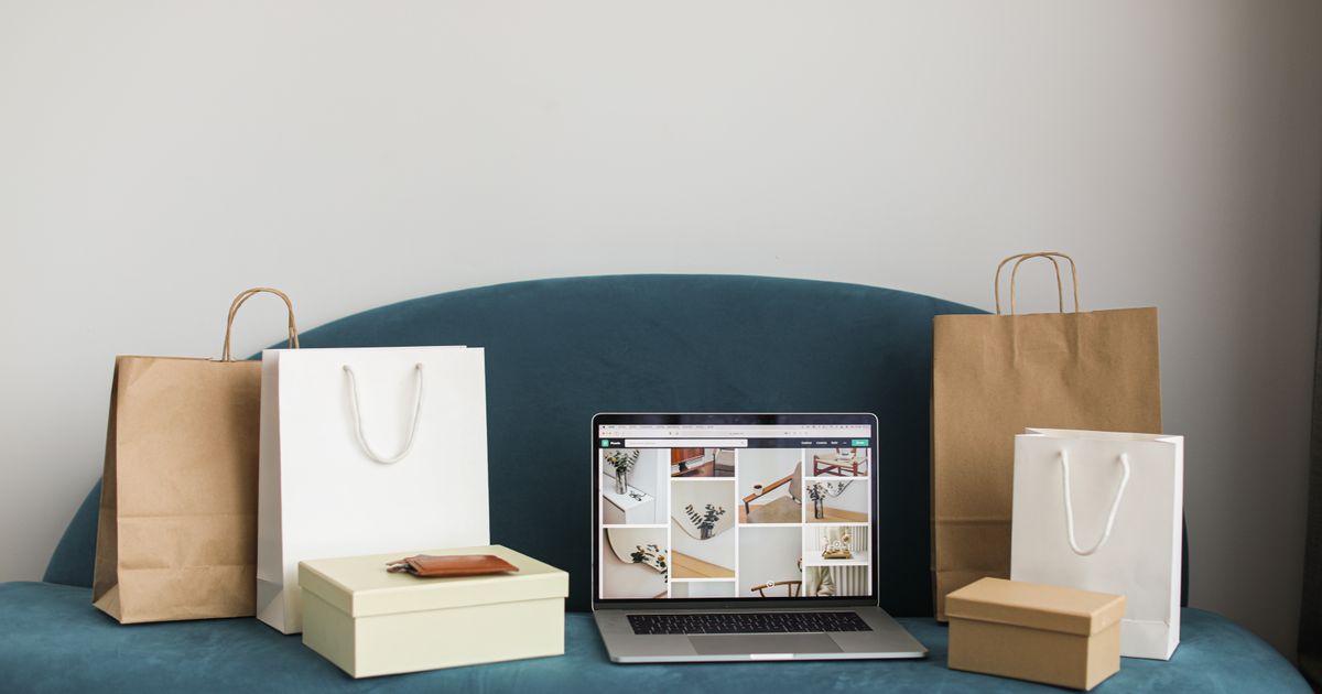 Laptop surrounded by shopping bags and parcels on a sofa, illustrating e-commerce marketing in Singapore.