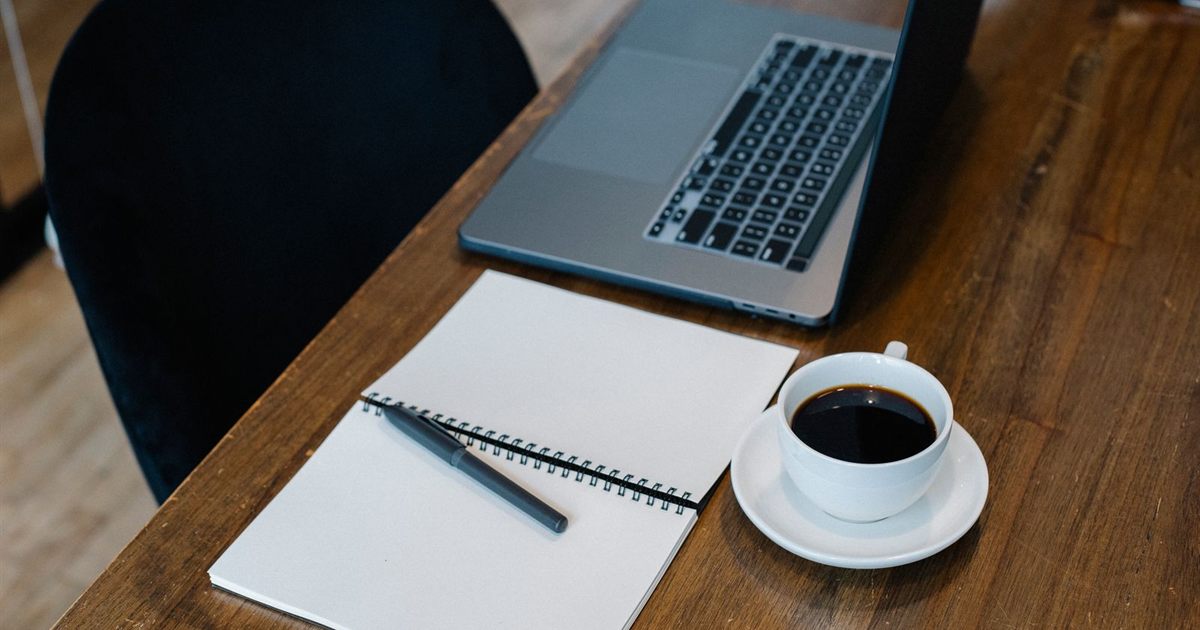 Notebook, pen and laptop on a desk, ready for drafting Facebook ad copy