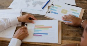 Two colleagues reviewing printed marketing charts and bar graphs together at a desk