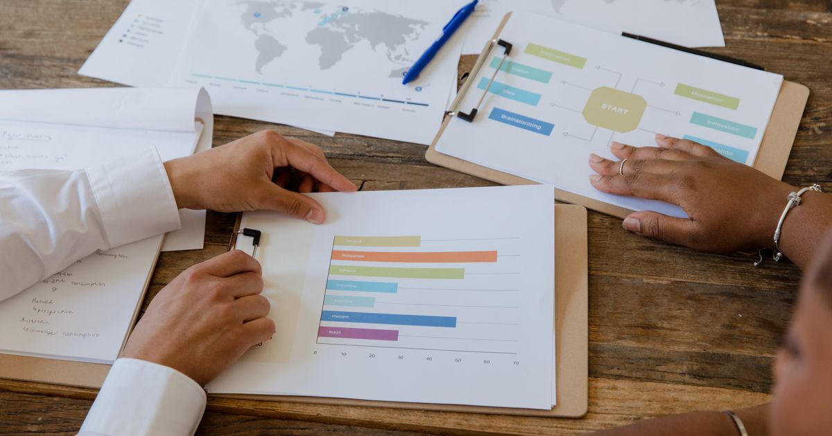 Two colleagues reviewing printed marketing charts and bar graphs together at a desk