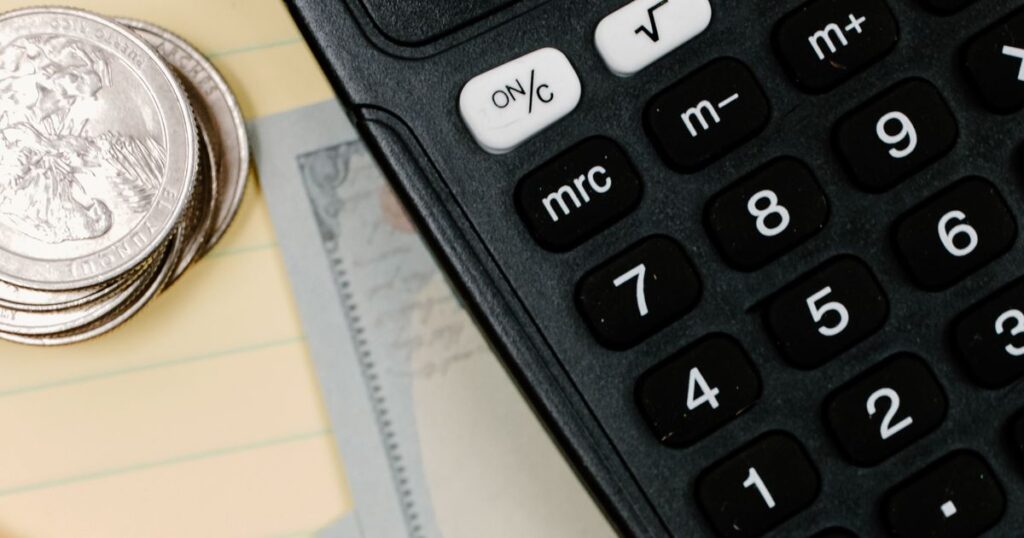Calculator, coins and cash on a notepad, representing setting a Google Ads budget