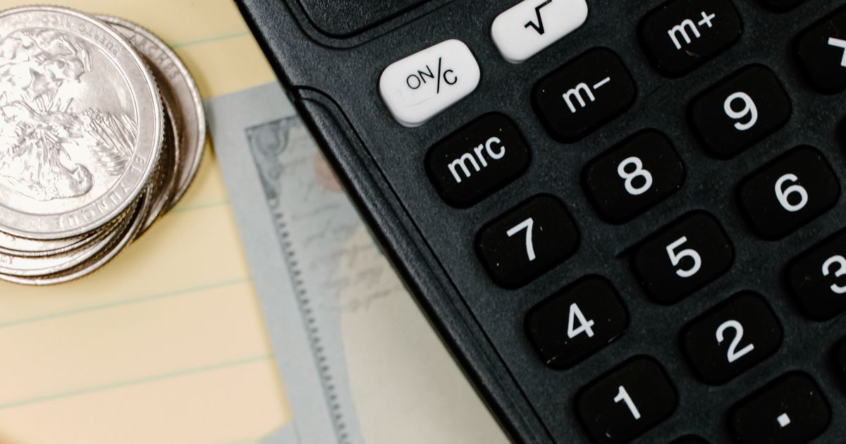 Calculator, coins and cash on a notepad, representing setting a Google Ads budget