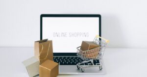 Laptop displaying online shopping with parcels and a cart, representing Google Shopping campaigns