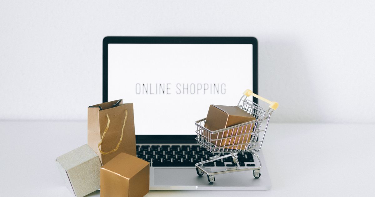 Laptop displaying online shopping with parcels and a cart, representing Google Shopping campaigns