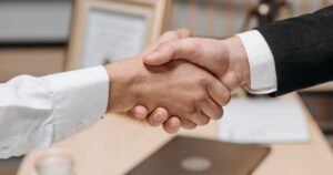 Two people shaking hands in an office, representing choosing and appointing an SEO agency