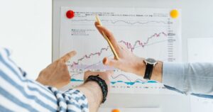 Colleagues analysing financial performance charts at a whiteboard during a business meeting.