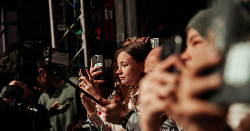 A crowd of people at an outdoor event holding up smartphones, representing a digital advertising audience