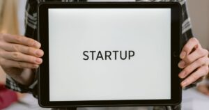 Person holding a tablet displaying the word startup, representing SEO for a newly launched website