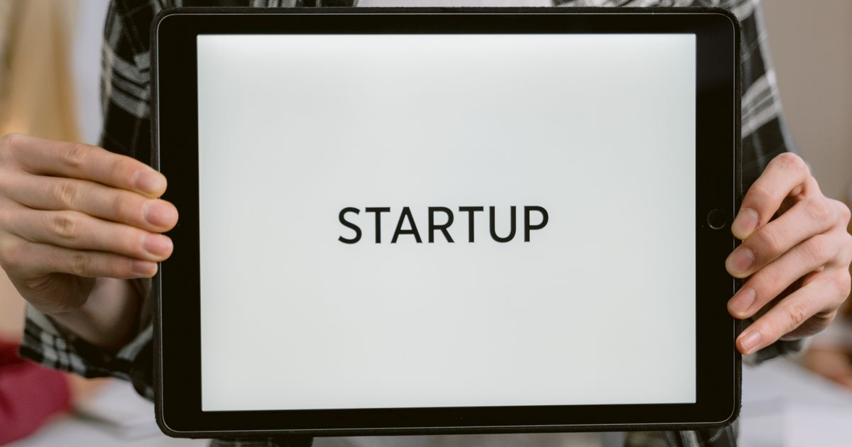 Person holding a tablet displaying the word startup, representing SEO for a newly launched website