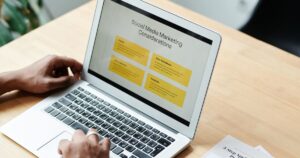 Marketer reviewing social media marketing performance on a laptop while planning an account audit.