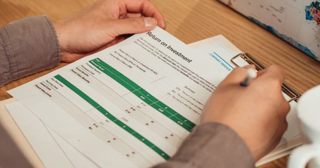 Marketer analysing a return on investment report with a pen, reviewing performance figures at a desk.