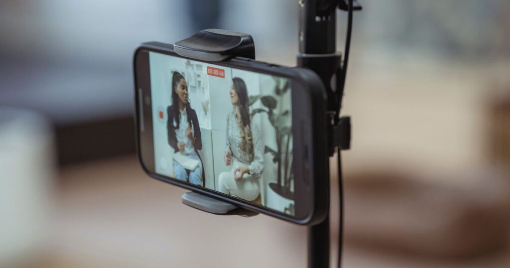 Smartphone mounted on a tripod recording a short-form video of two people talking