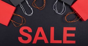 Red and black paper shopping bags arranged around the word SALE, representing an online mega-sale campaign