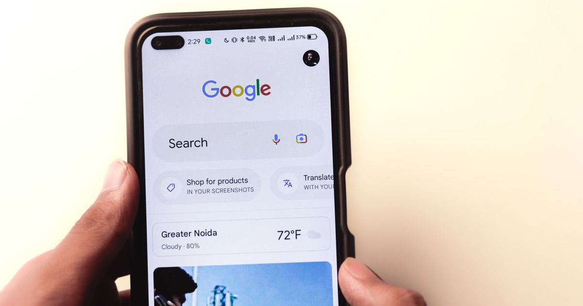 Hand holding a smartphone with the Google search app open, where AI Overviews now appear above the results