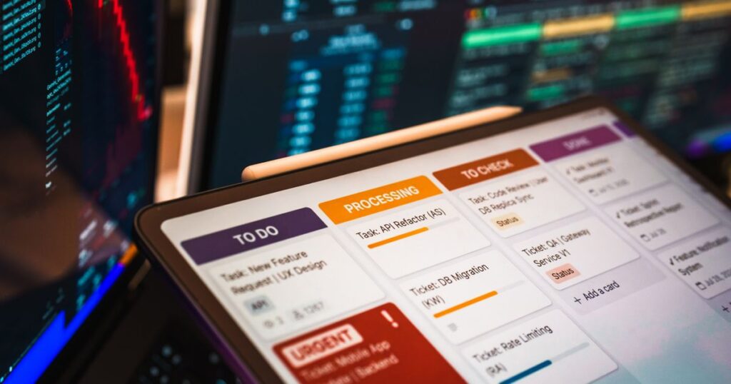 A marketing platform dashboard open on a tablet in front of monitors showing live data feeds