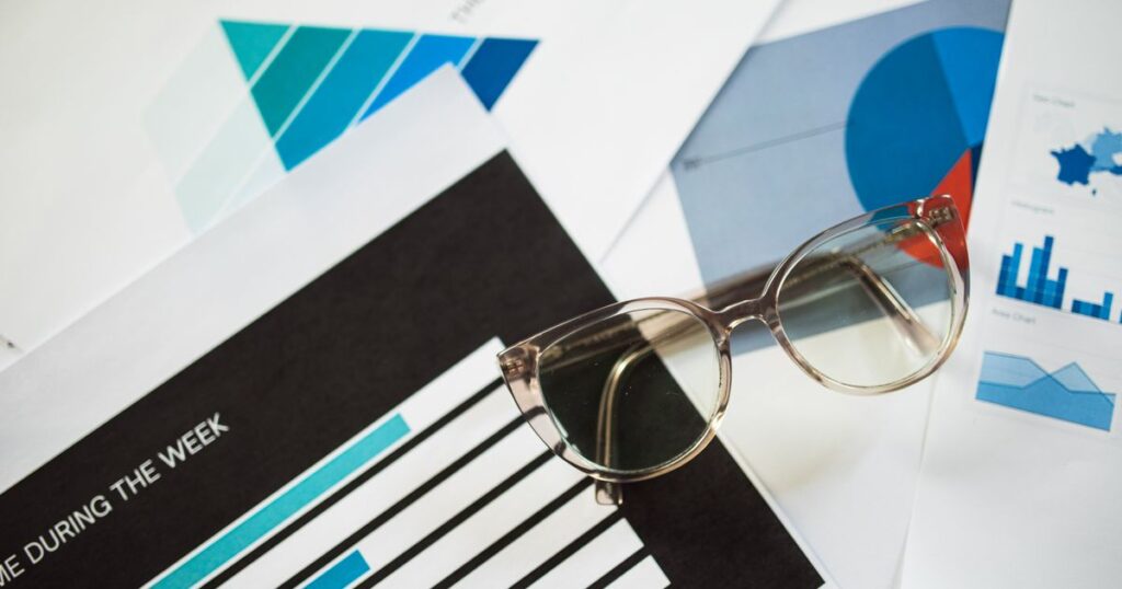 Reading glasses resting on printed reports full of bar charts and graphs