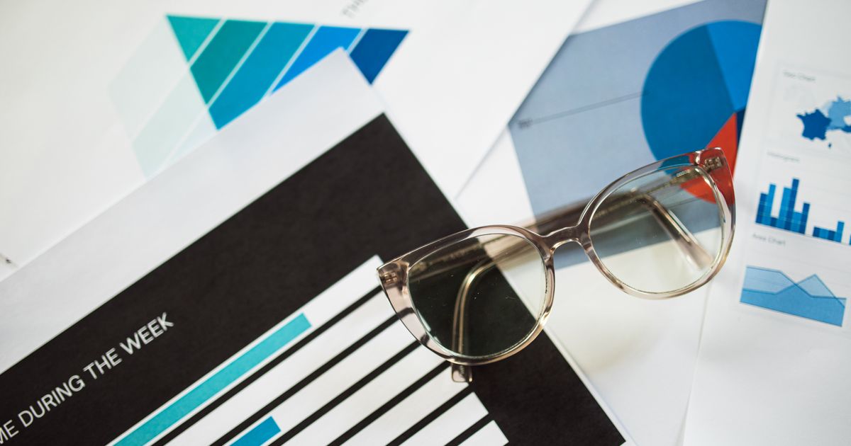 Reading glasses resting on printed reports full of bar charts and graphs