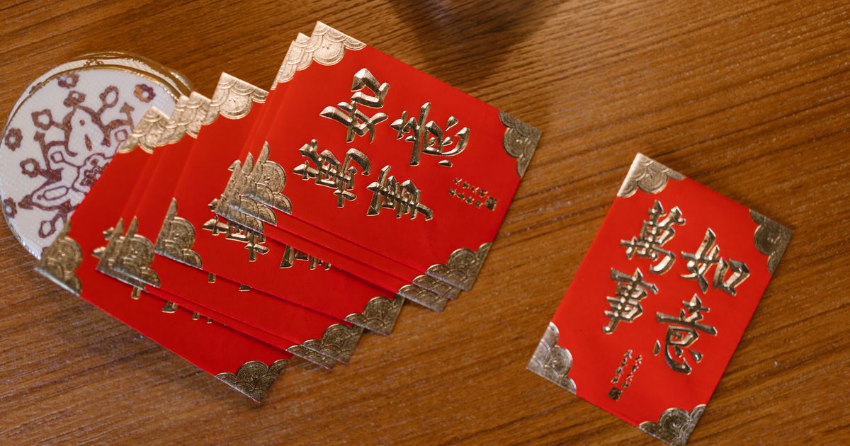 Traditional red Chinese New Year envelopes with gold lettering fanned out on a wooden table