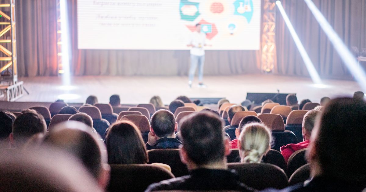 Audience seated in a hall listening to a speaker present at a public health talk