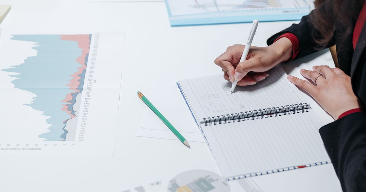 Marketer taking notes beside printed performance charts while reviewing results.