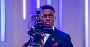 A videographer in a suit operating a tripod-mounted video camera at a corporate event