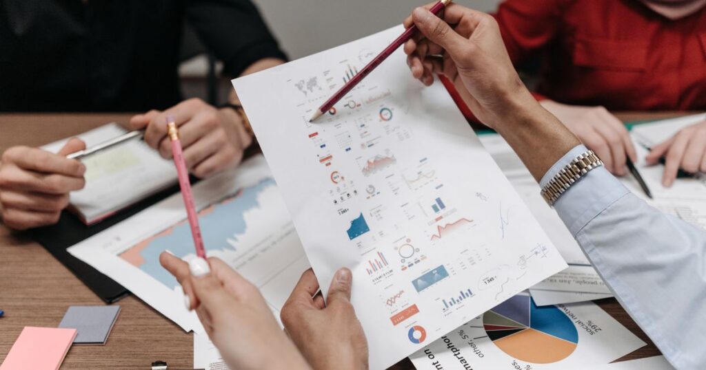 Team reviewing printed marketing charts and reports together at a meeting table