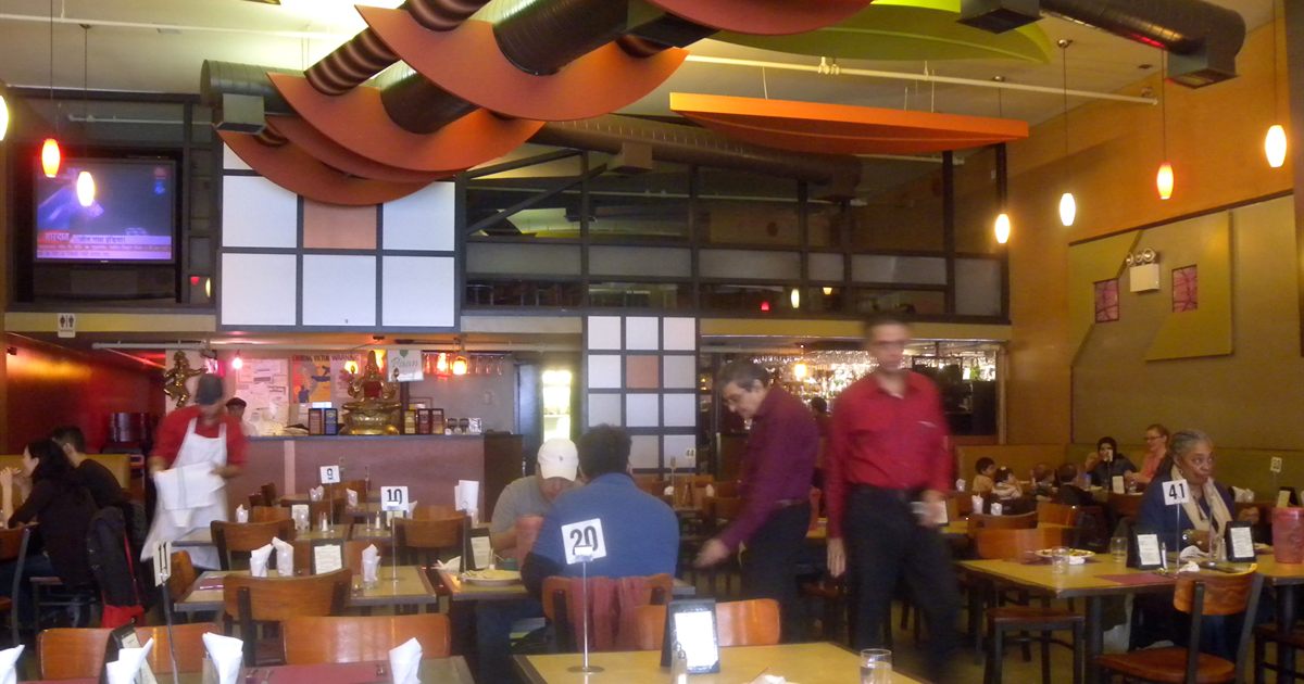 Waiting staff serving customers at tables in a busy restaurant dining room
