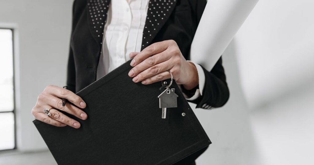 Property agent holding a clipboard and a house-shaped keyring in an empty apartment