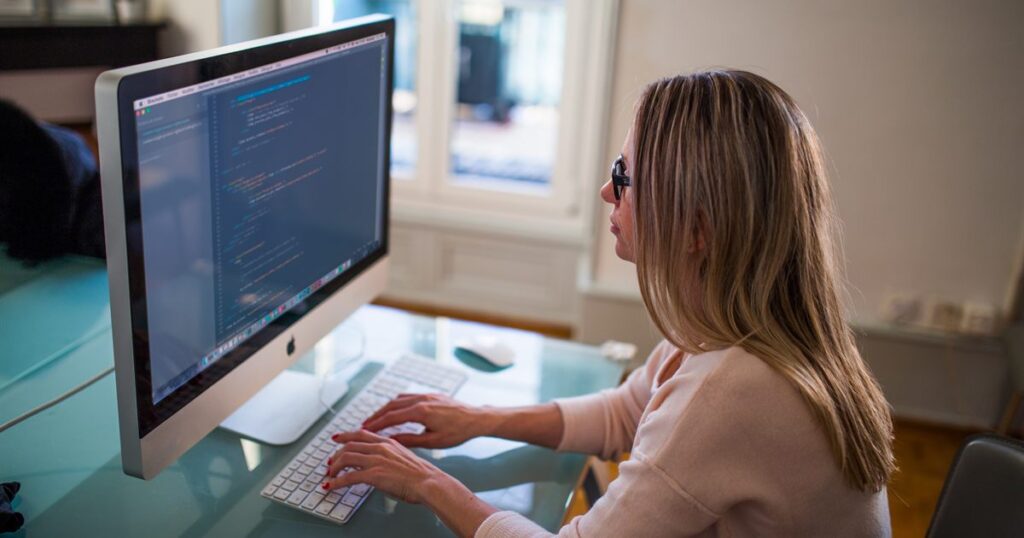 Writer working on a blog post at a desktop computer in a home office
