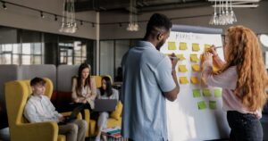 A marketing team planning strategy with sticky notes on a whiteboard in a shared office