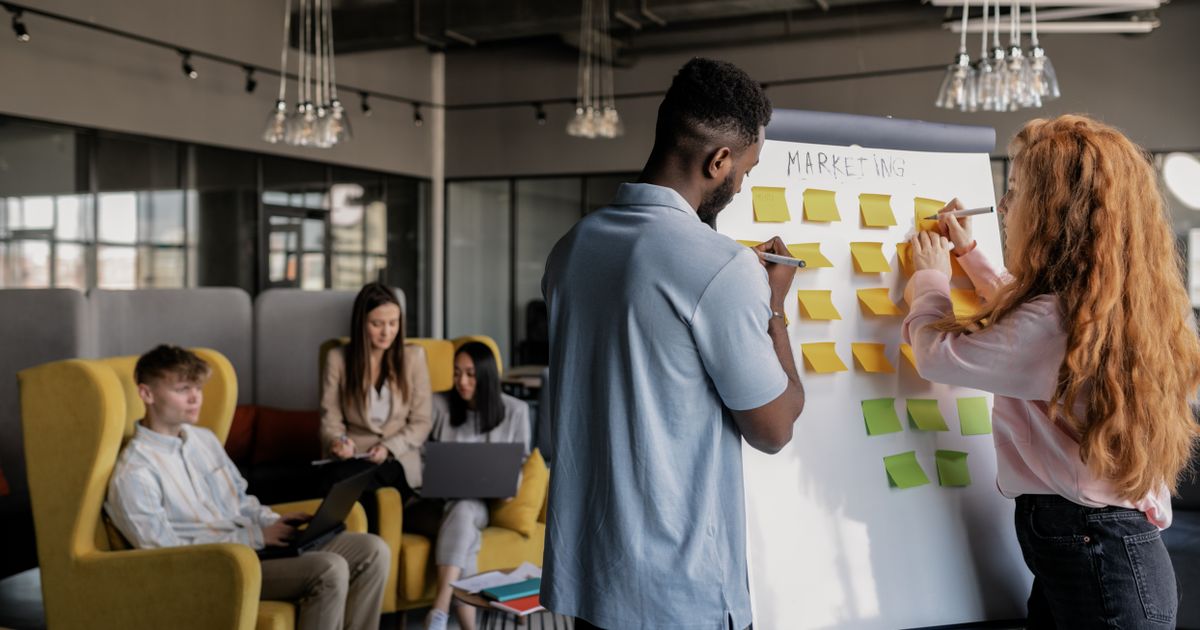 A marketing team planning strategy with sticky notes on a whiteboard in a shared office