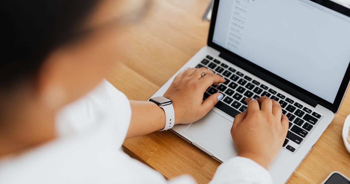 Marketer working through an email campaign on a laptop at a wooden desk