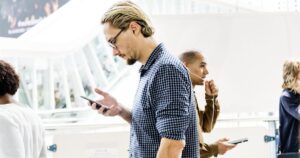 Commuters reading content on their phones in a busy public walkway