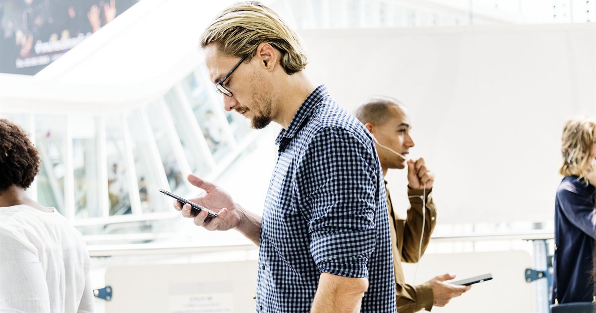 Commuters reading content on their phones in a busy public walkway