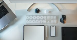 Overhead view of a desk with a laptop, monitor, tablet and smartphone arranged side by side