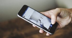 A hand holding a smartphone with a social media feed open on screen