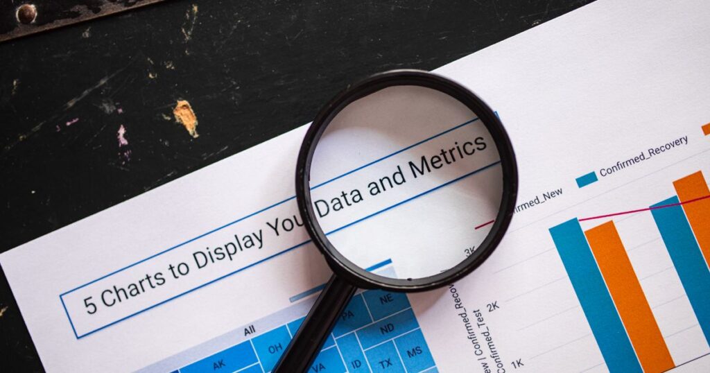 Magnifying glass held over a printed marketing report showing charts and metrics