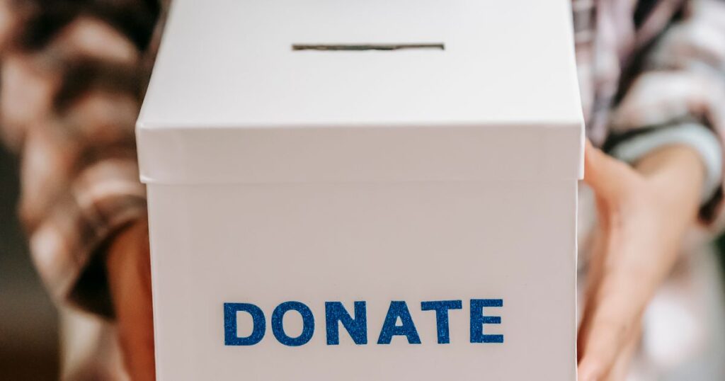 A plain white donation box marked DONATE held out towards the camera.