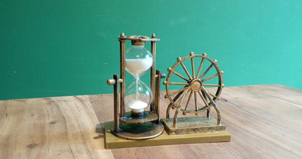 A brass hourglass with white sand running on a wooden table, illustrating the false urgency tactics such as countdown timers that CCS treats as unfair in Singapore.