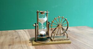 A brass hourglass with white sand running on a wooden table, illustrating the false urgency tactics such as countdown timers that CCS treats as unfair in Singapore.