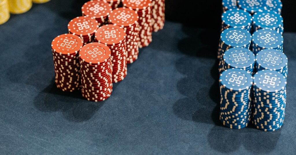 Stacks of red and blue unbranded casino chips on a dark blue gaming table.
