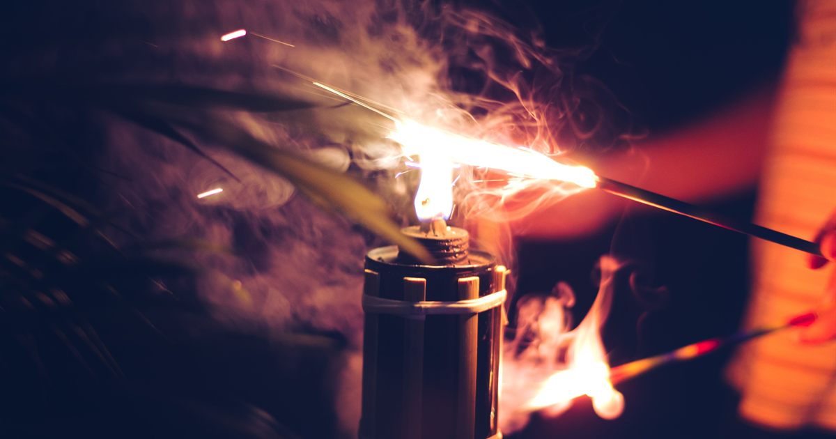 A traditional pelita oil lamp being lit at dusk during the Hari Raya festive season