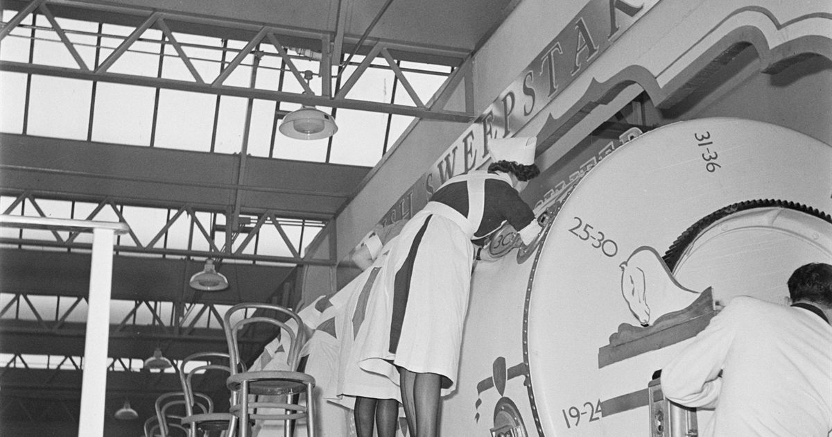 A large numbered sweepstake drum being operated under supervision at a public prize draw