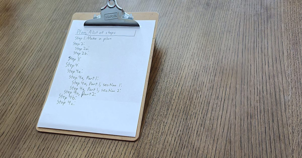 A clipboard on a wooden desk holding a handwritten plan headed with a list of steps, used to illustrate an NRIC data migration checklist