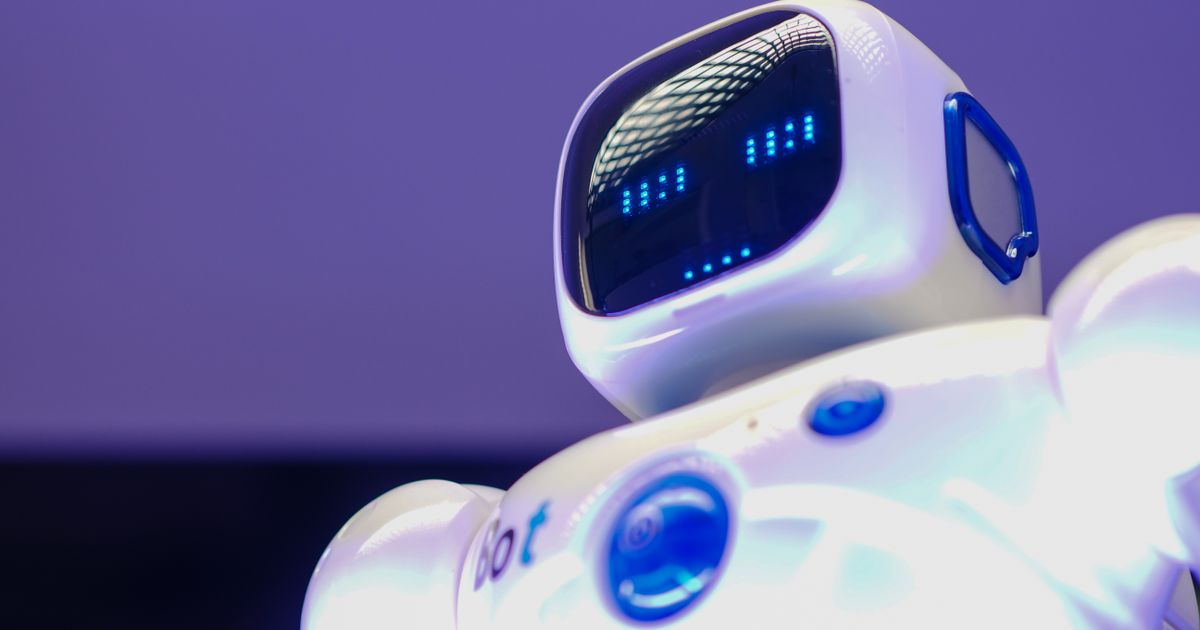Close-up of a small white robot with glowing blue LED eyes, illustrating the PDPA and consumer-protection rules for AI chatbots on Singapore business websites.