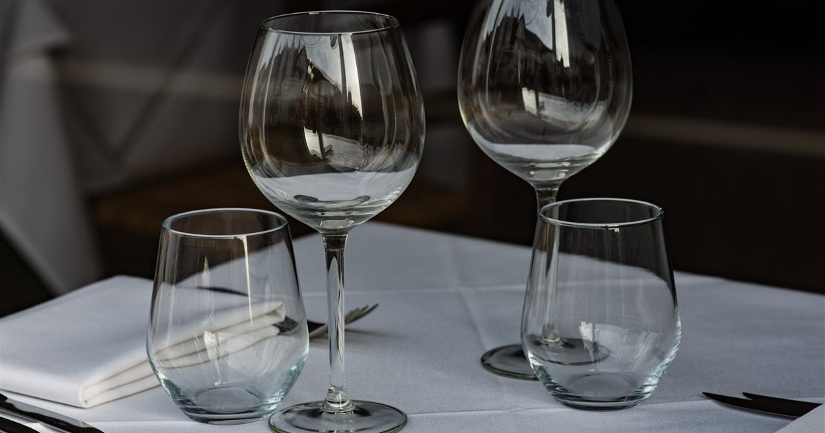 Empty wine glasses and tumblers on a white tablecloth at a restaurant table, illustrating the rules on advertising and marketing alcohol in Singapore.