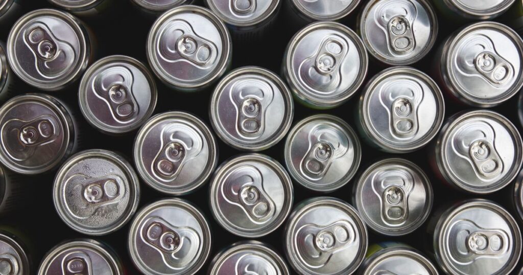 Rows of unbranded silver drink can tops seen from above, illustrating how Singapore's Beverage Container Return Scheme deposit affects how drinks are priced and promoted.
