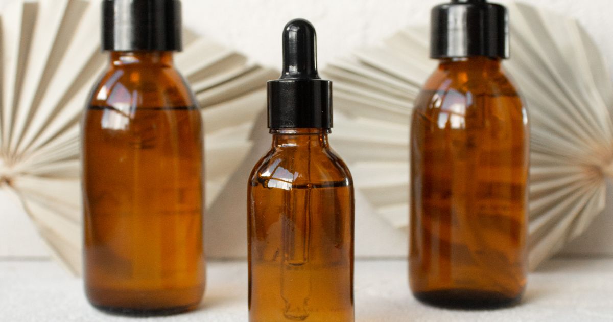 Three unbranded amber glass dropper bottles of skincare serum on a pale surface, illustrating the rules for advertising cosmetic product claims in Singapore.